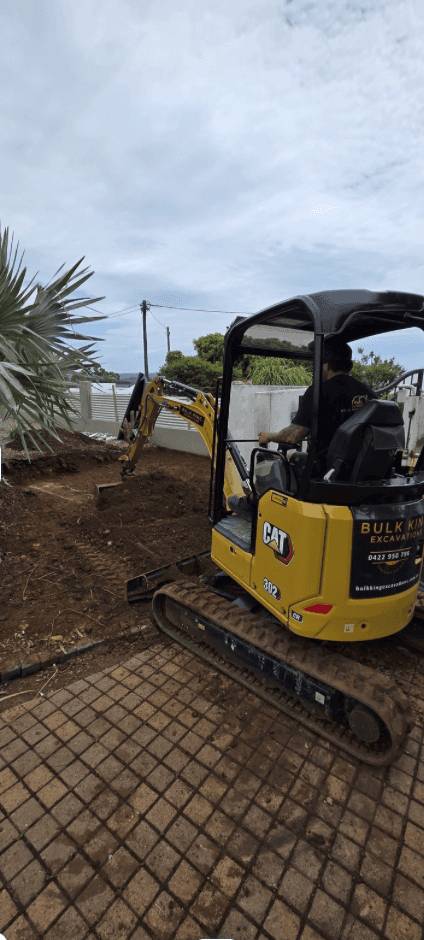 Mini excavator cutting a building pad beside a new home, Sunshine Coast