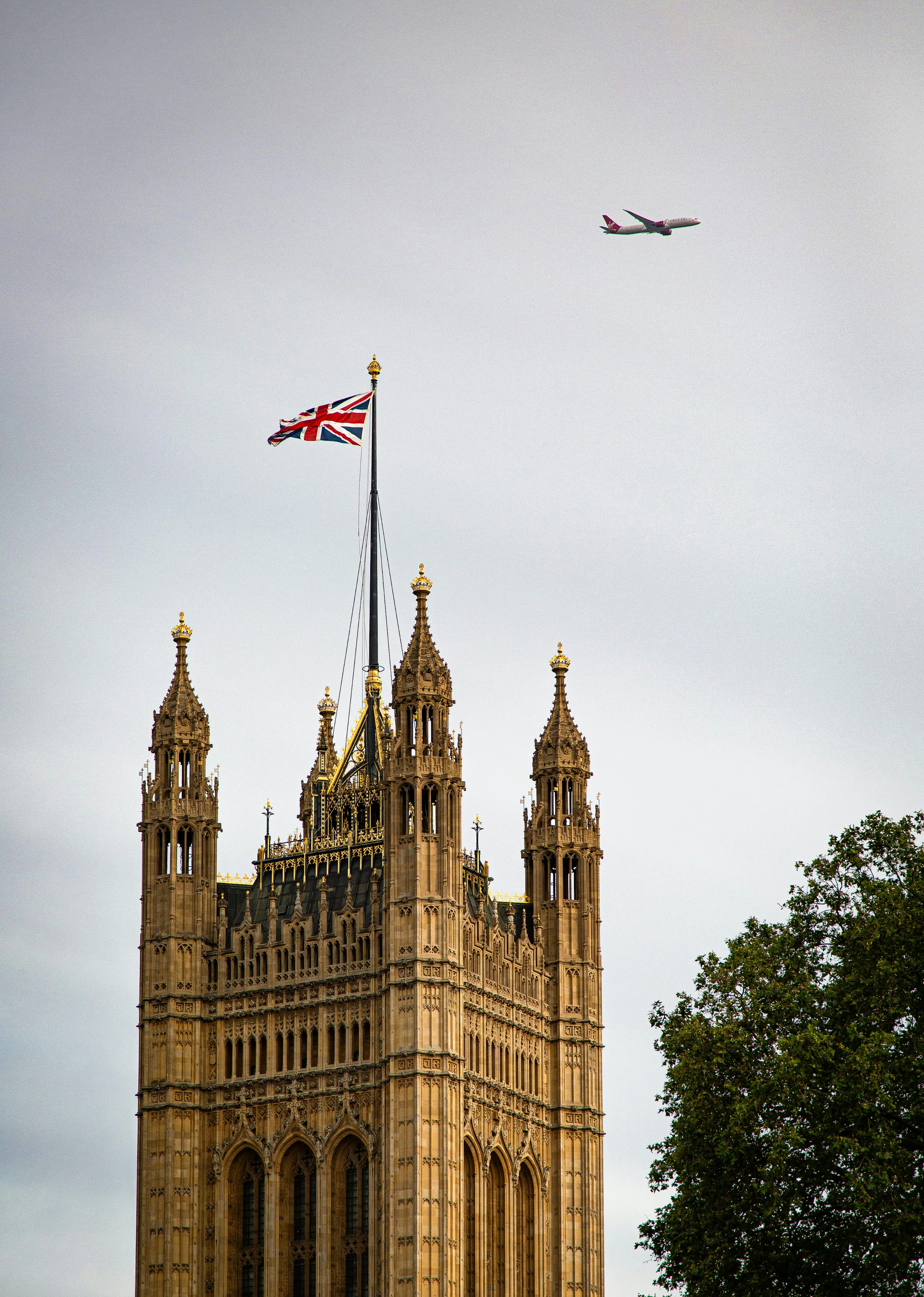 One of the ornate towers of the Palace of Westminster, with a British flag flying above.