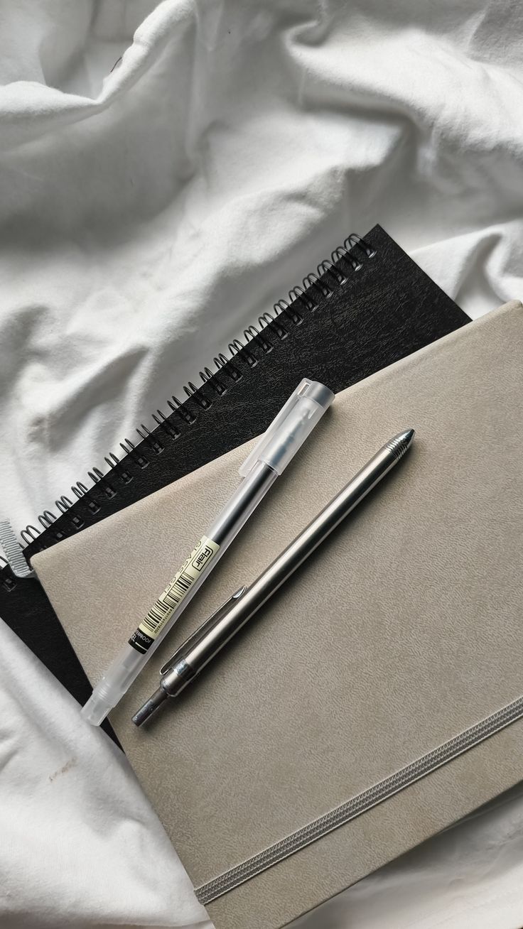 A young person with curly hair smiles at the camera while sitting in front of a laptop against a dark background.