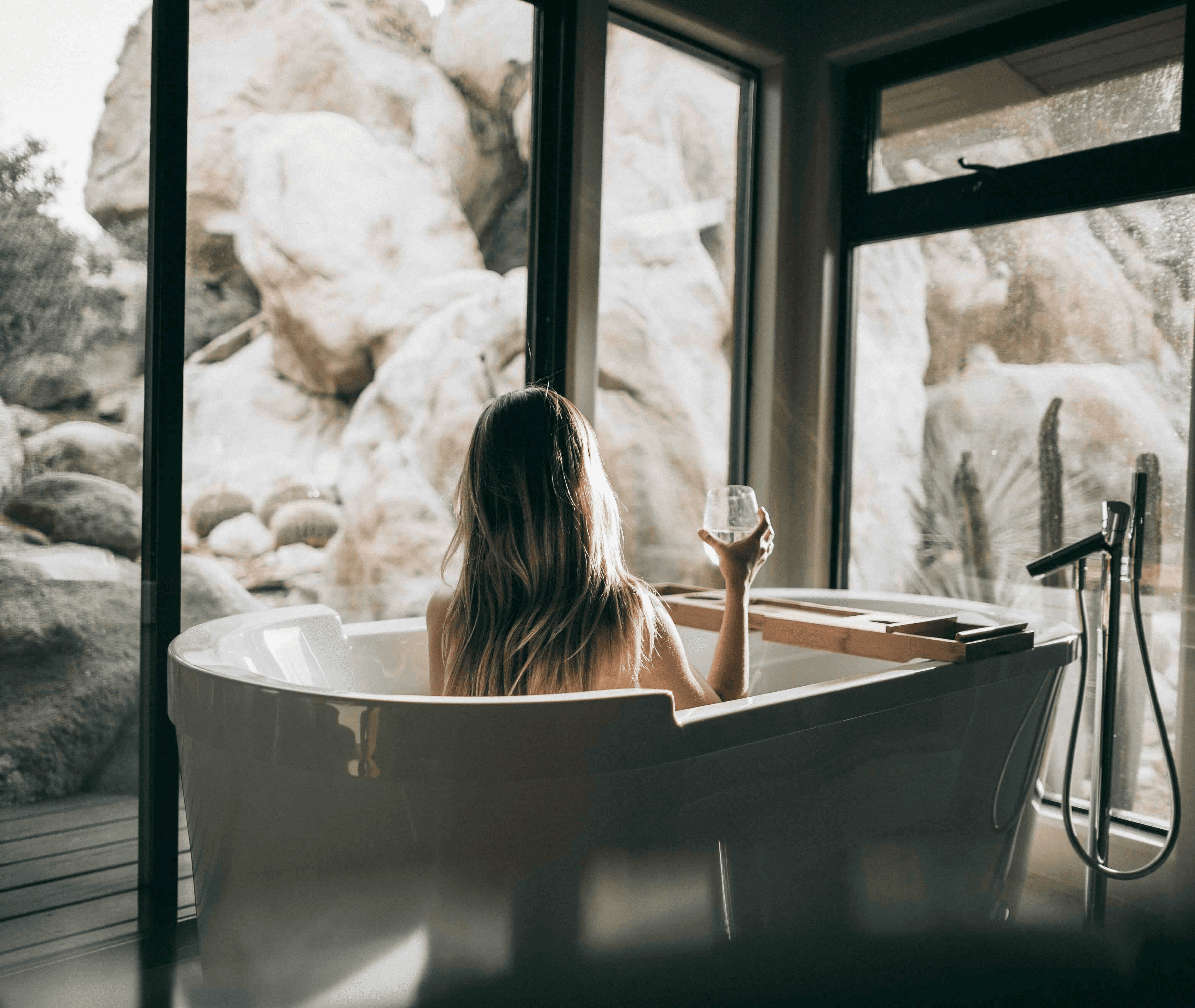 Guest relaxing in a freestanding bath overlooking a rocky landscape