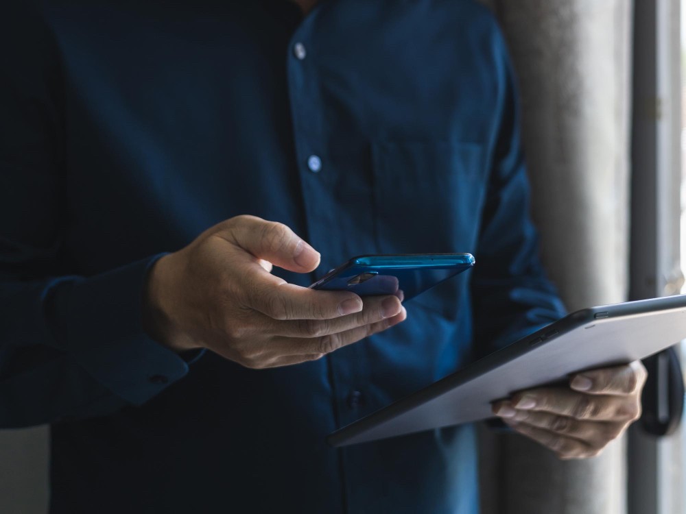 Person holding a smartphone and checking tasks, representing digital checklists for operational accountability.