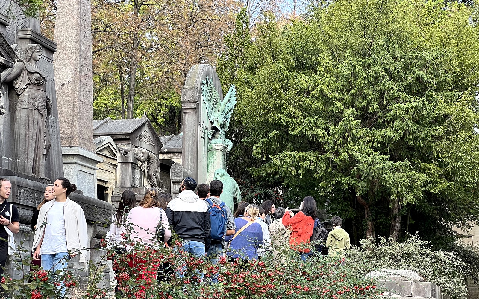 一组游客在巴黎拉雪兹公墓参观雕像和墓碑。