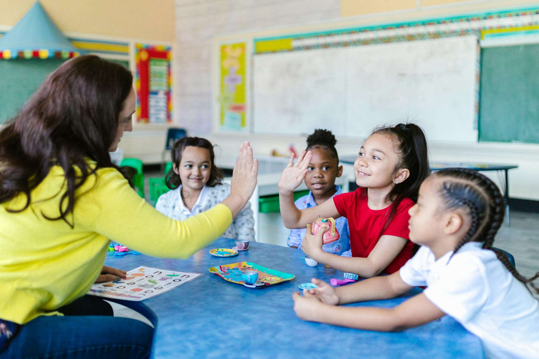 A diverse group of middle school students sitting in a circle on a rug, smiling and performing a rhythmic handclap.