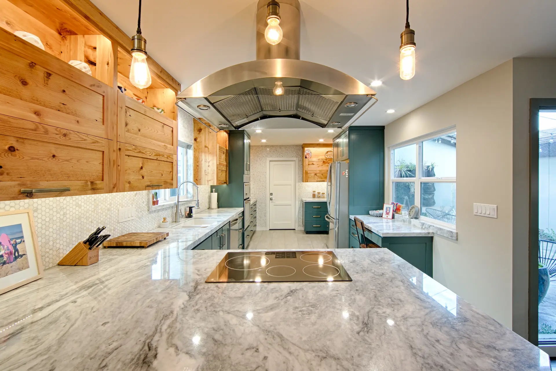 Stylish kitchen with marble island, pendant lights, and wood paneling in Huntington Beach Kitchen & Bath Remodel.
