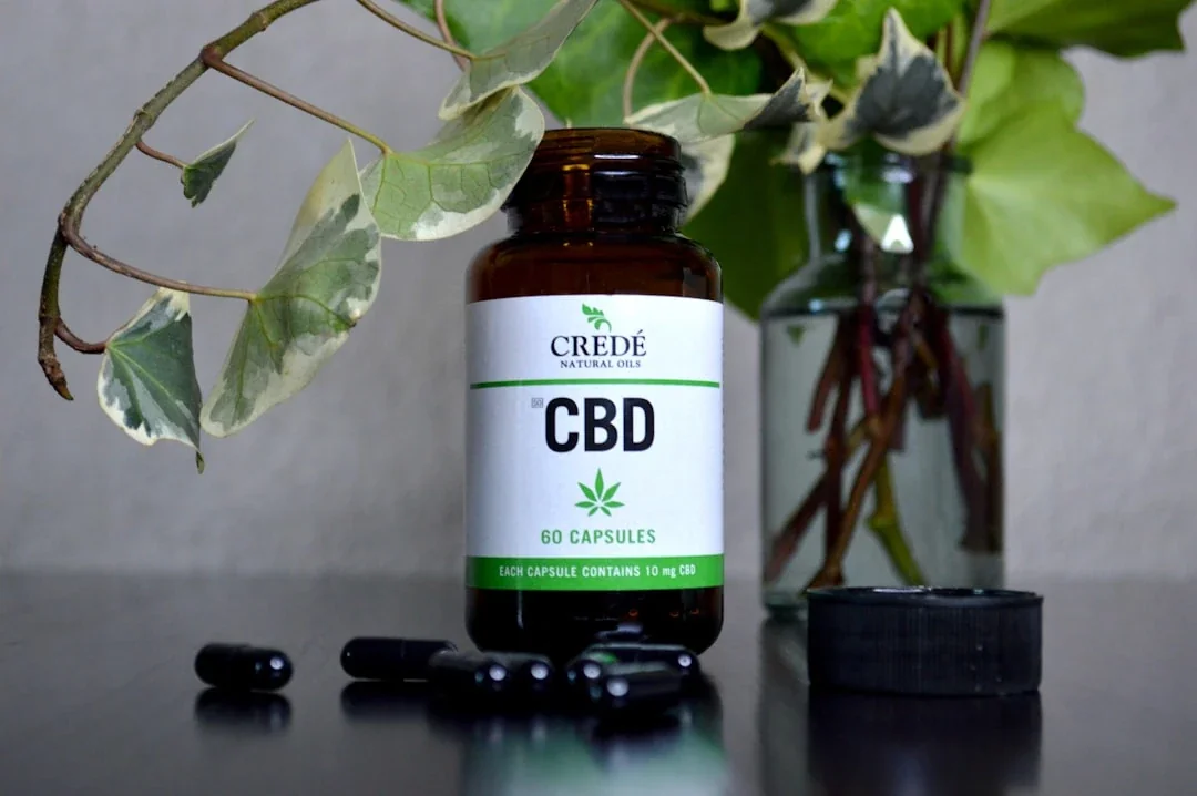 a bottle of cbd sitting next to a vase of flowers
