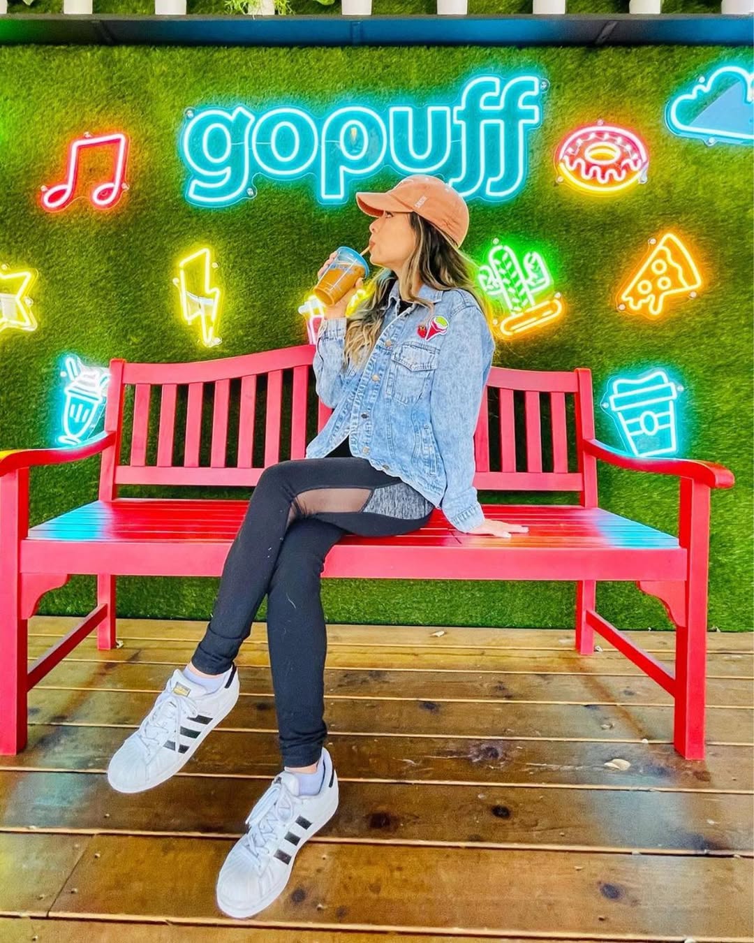 Black hanging storefront sign reading “sol studio” mounted on a metal bracket against a light stucco building, with string lights overhead and a blue sky with scattered clouds in the background.