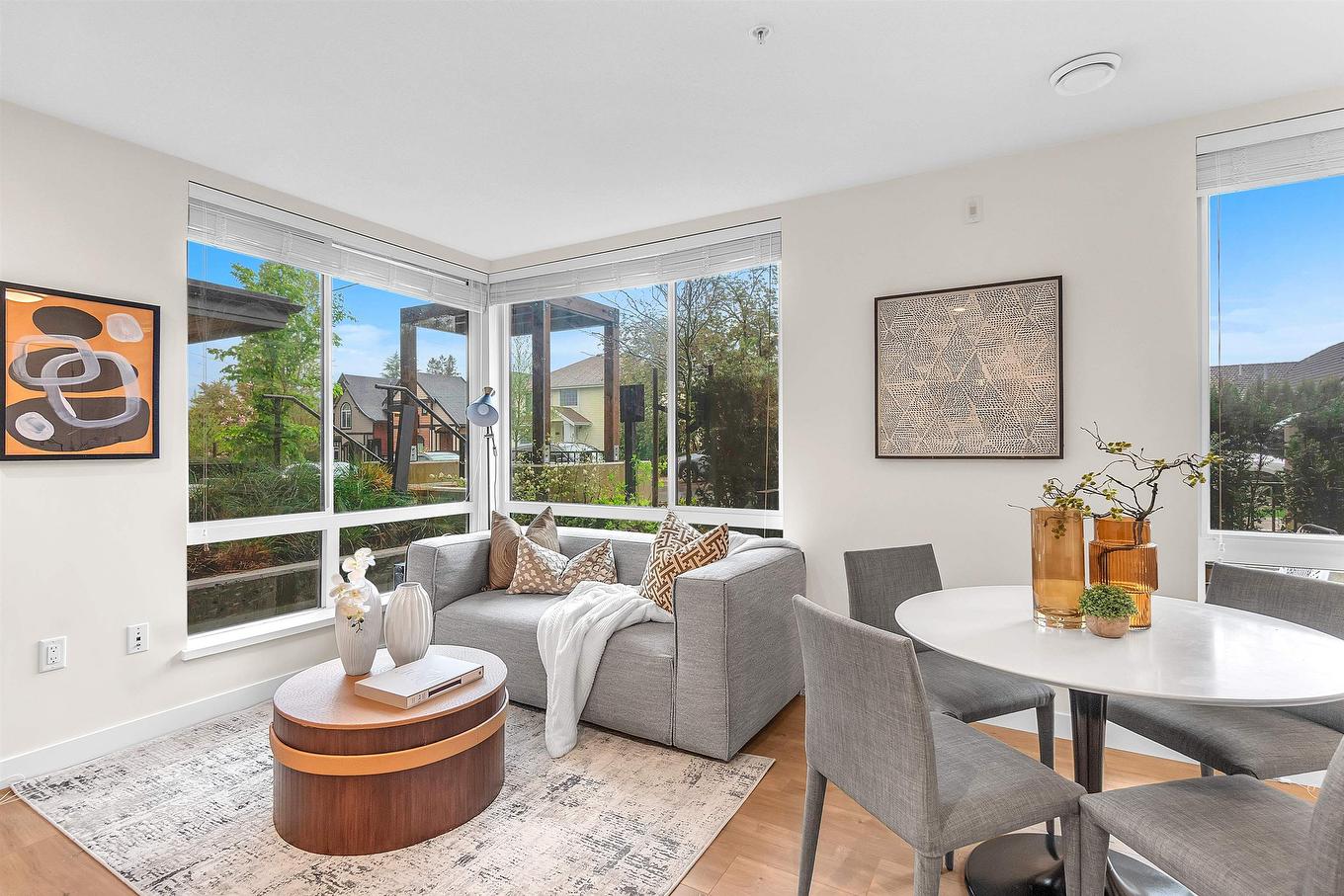 Bright and cozy living area with large windows, modern furniture, and a dining table, featuring outdoor views.