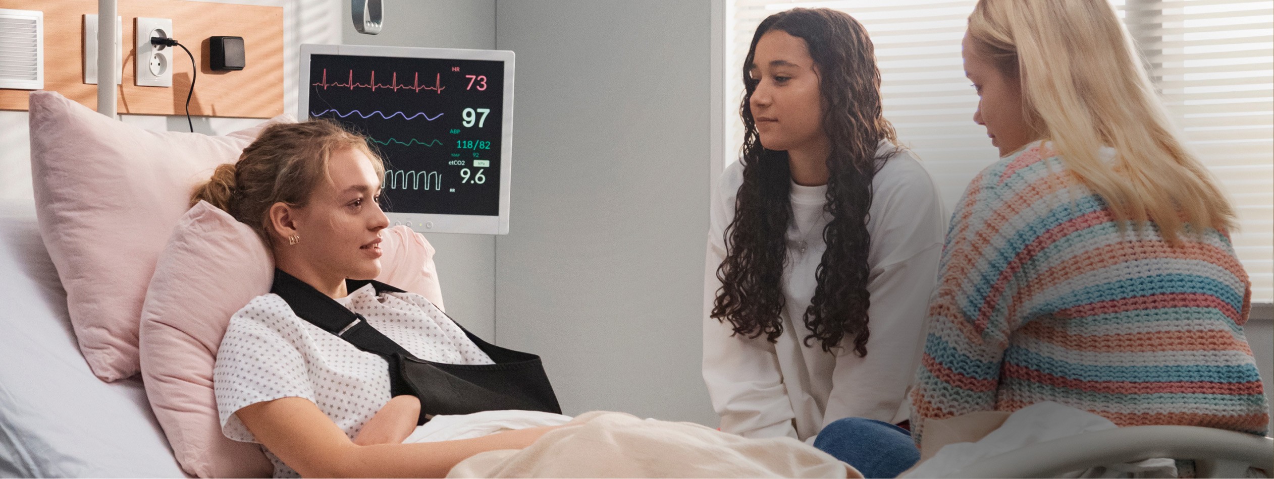 A woman named Jenny O with black hair smiles while sitting on a wooden surface, with shelves in the background.