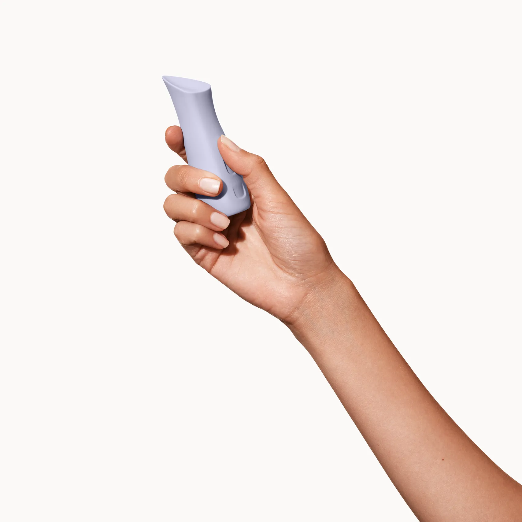 Hand holding a light gray Kip sexual wellness device on a white background