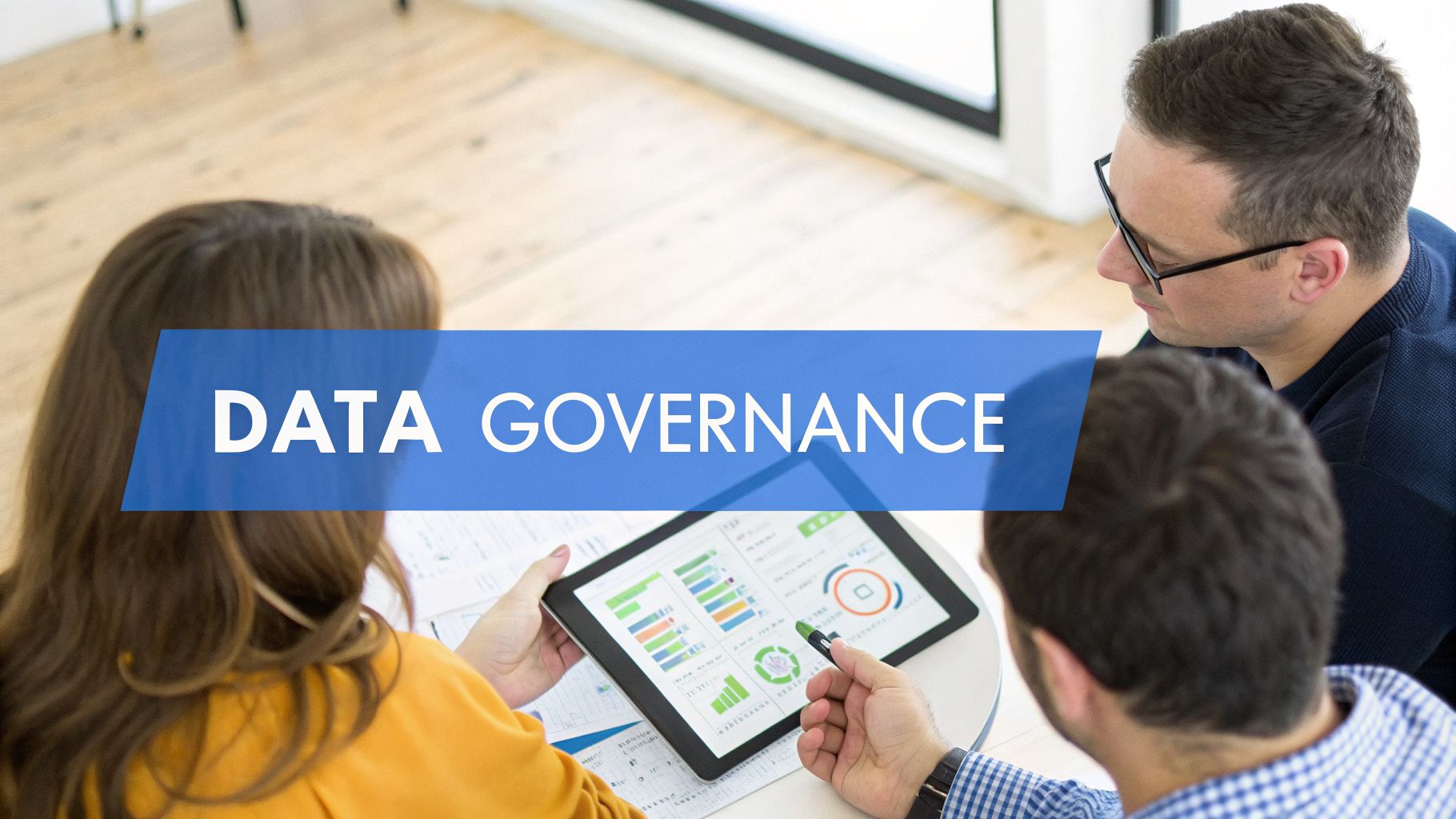 Three business professionals discuss data governance while viewing charts on a tablet.