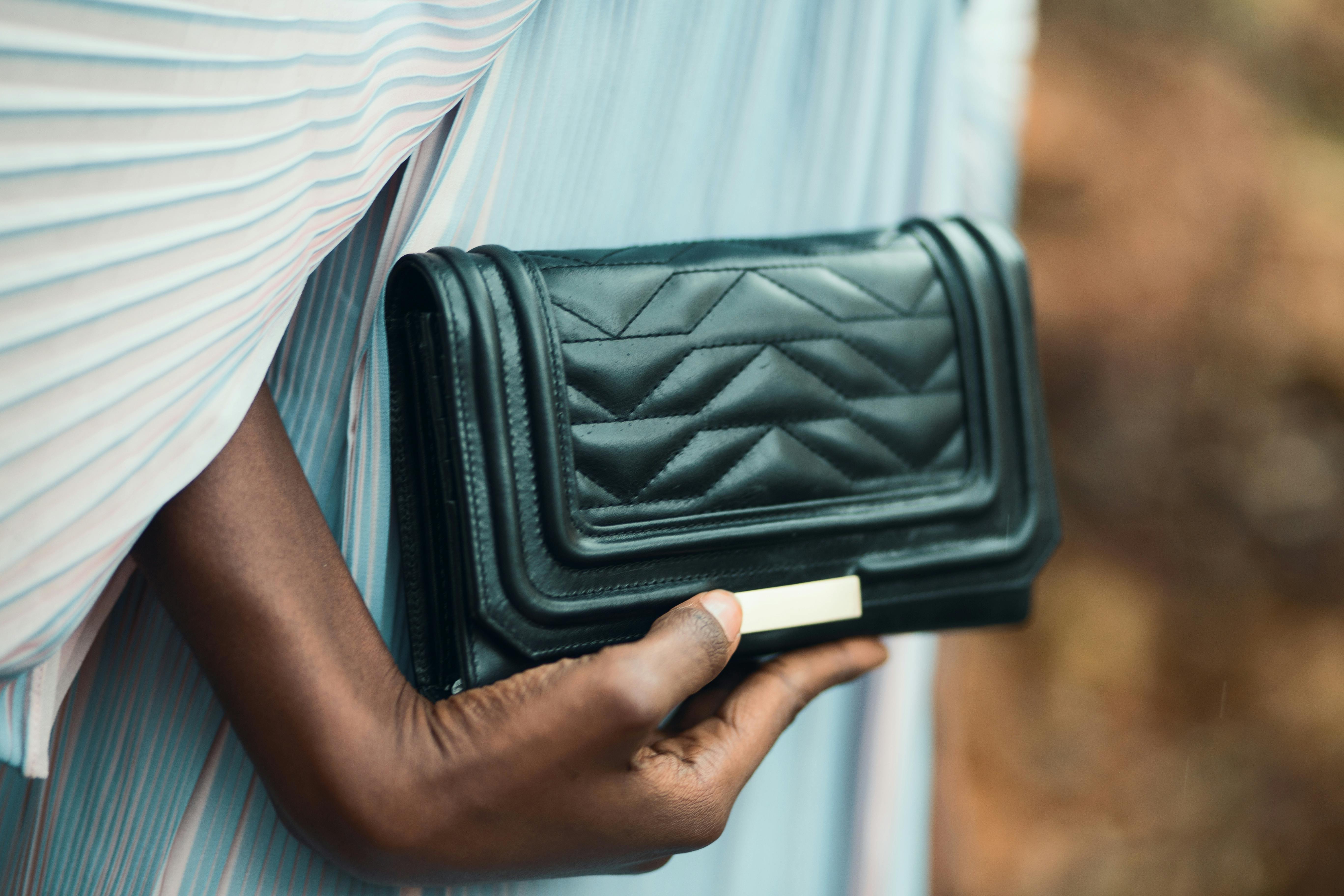 a hand clutching a black luxury mini purse