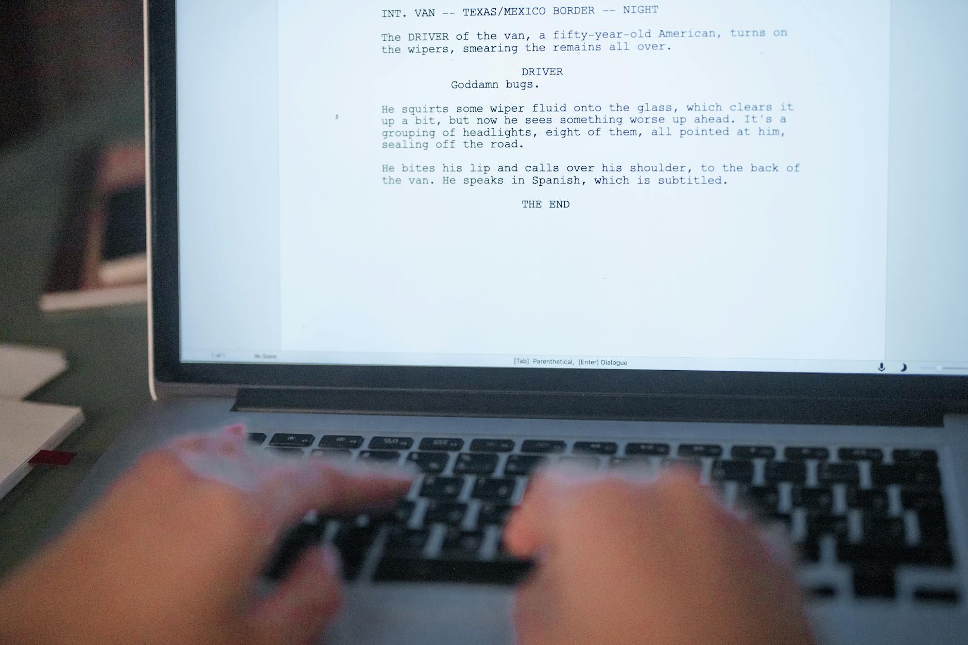 A woman sitting in a bright home office typing on a laptop with a blank website template visible on the screen.