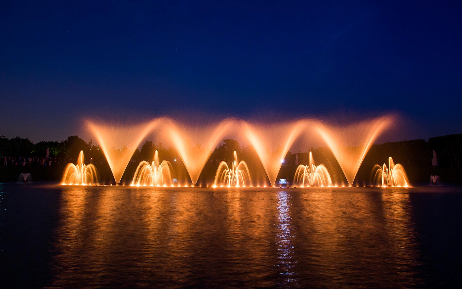Espectáculo de fuentes por la noche en los jardines del Palacio de Versalles, Francia.
