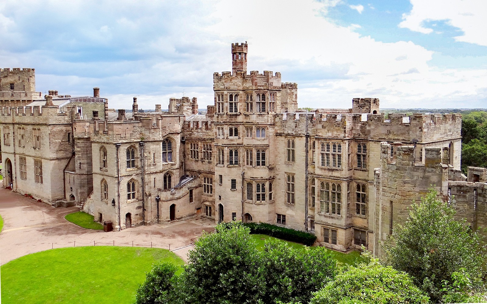 Warwick Castle exterior with stone towers and lush green grounds.