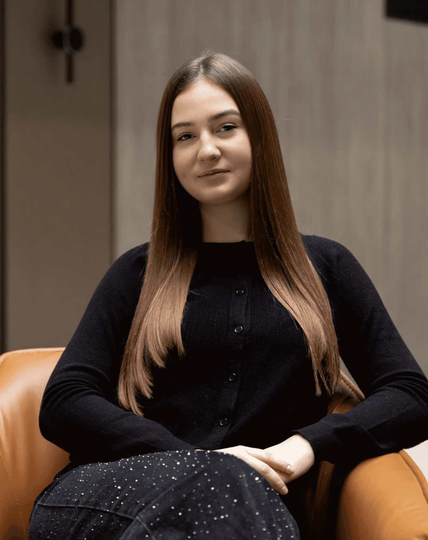 Casual studio portrait of a bearded man with curly hair in a white shirt, arms crossed, on a light gray background.