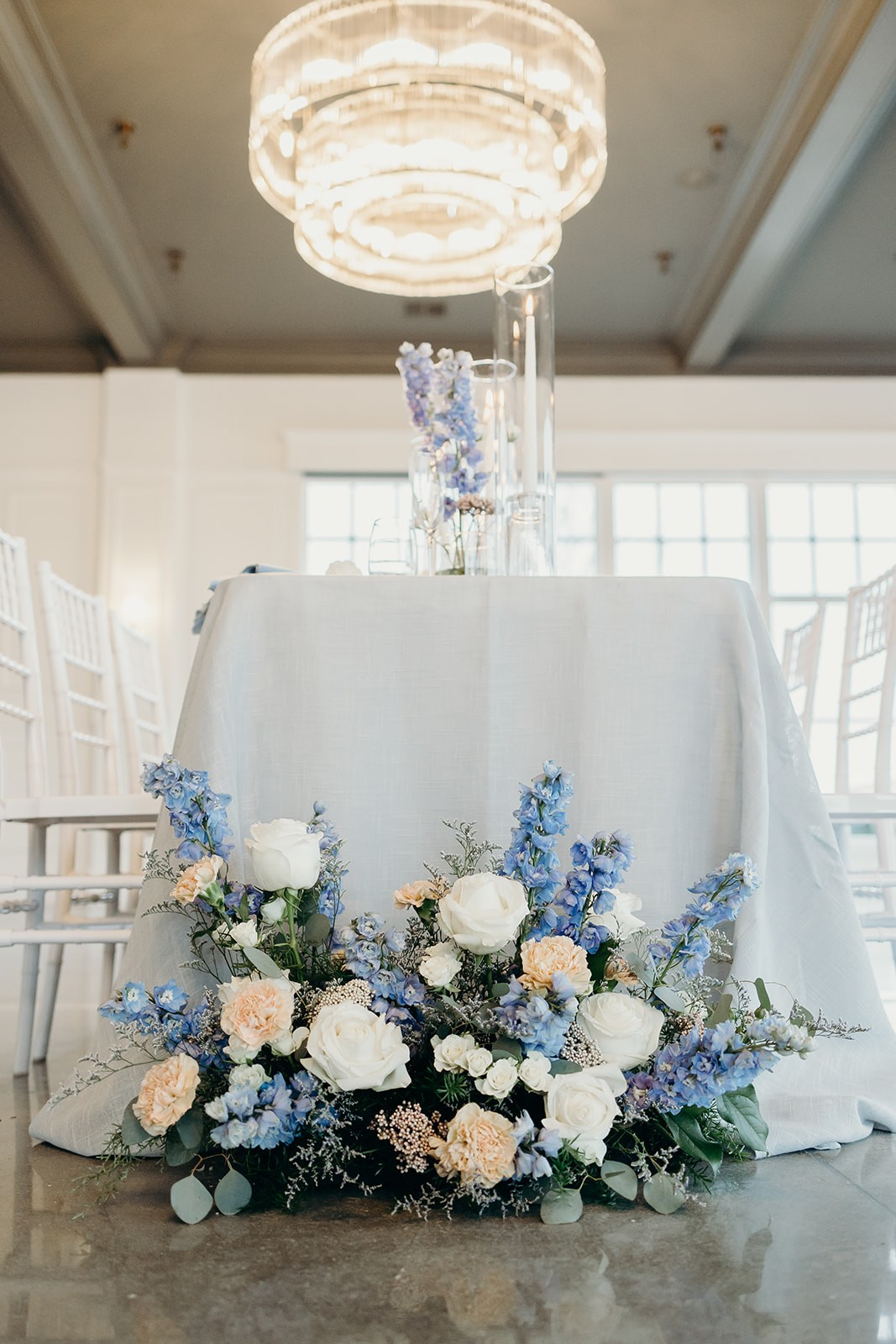 Floor centerpiece at an Iowan wedding, including white roses, blue delphinium, peach carnations.