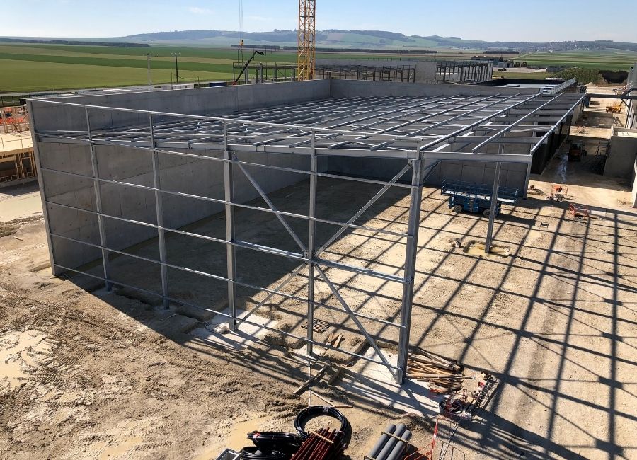 Vue rapprochée d’une fondation béton armé, avec armatures métalliques exposées prêtes pour coulage.