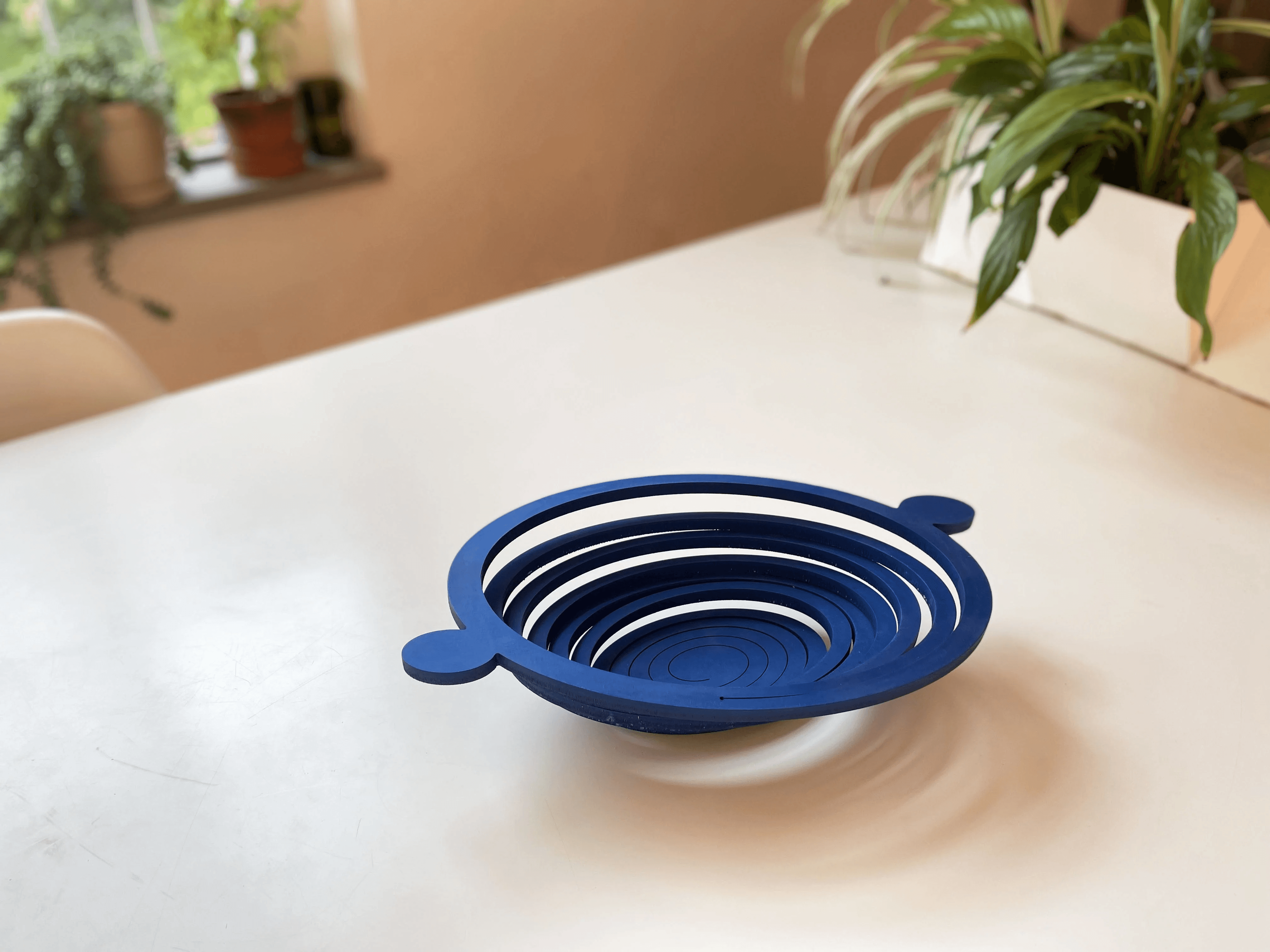 Clear glass bowl with handles on a reflective surface with swirling patterns and light highlights.