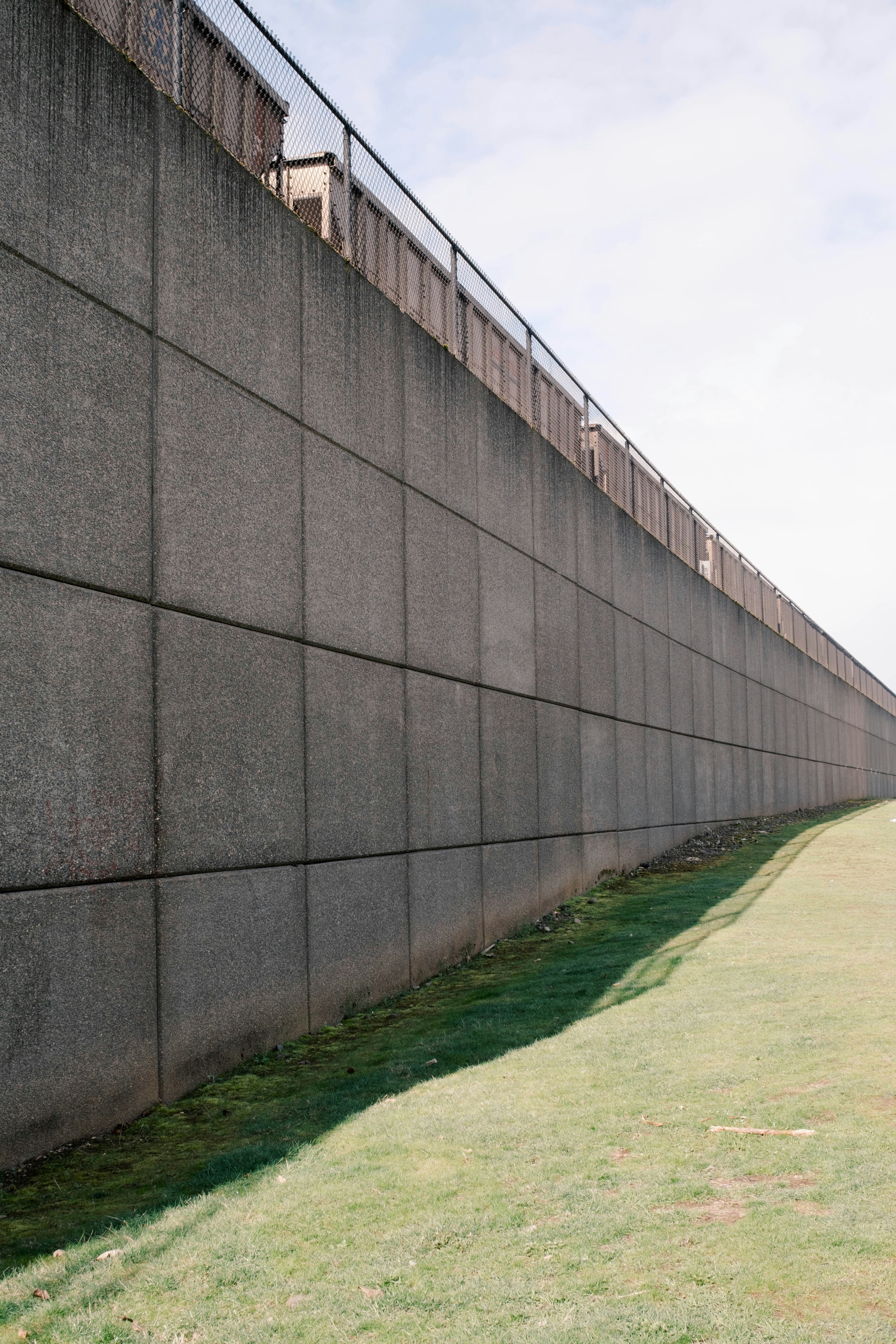 Long mur de soutènement en béton longeant un terrain gazonné.