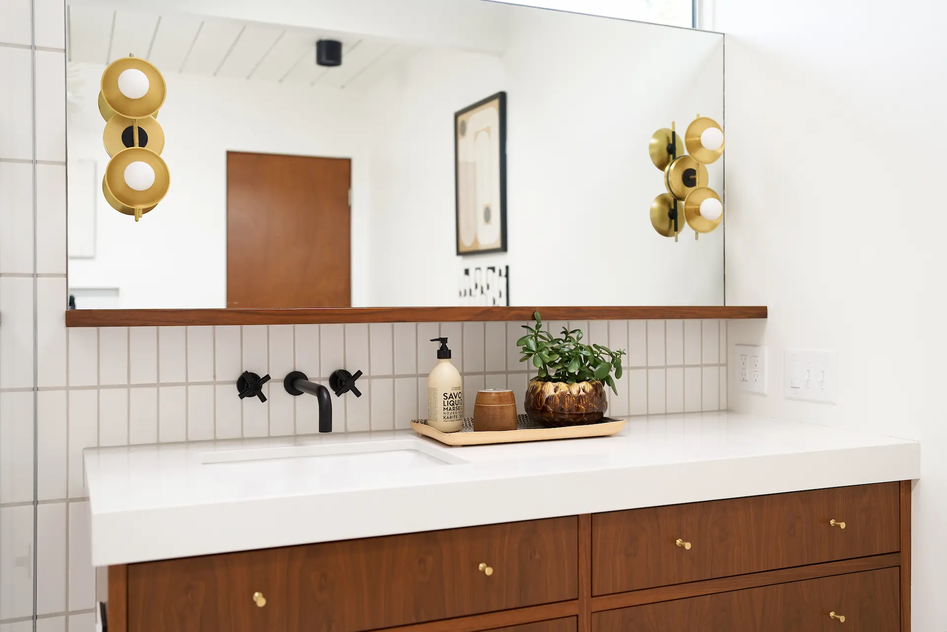 Close-up view of the primary bathroom vanity area, highlighting the sink, faucet, and mirror in the Fairhaven Eichler Tract remodel. Photo by Todd Huge.