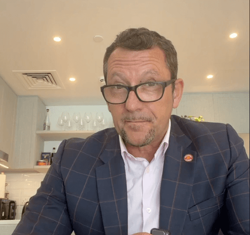 Video image showing a man with a suit talking to the camera