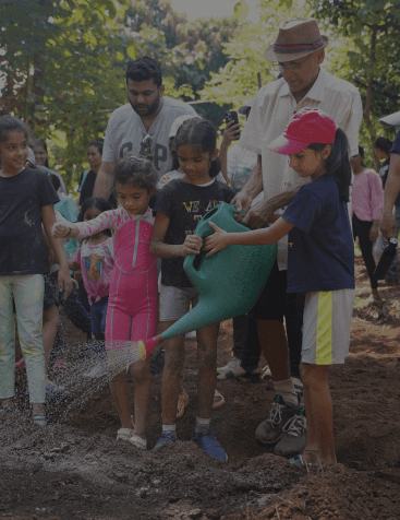 A gardner helping children and teaching them about gardening and importance of outdoors