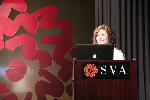 a woman giving a speech from a stand in the "designer as" thesis presentation