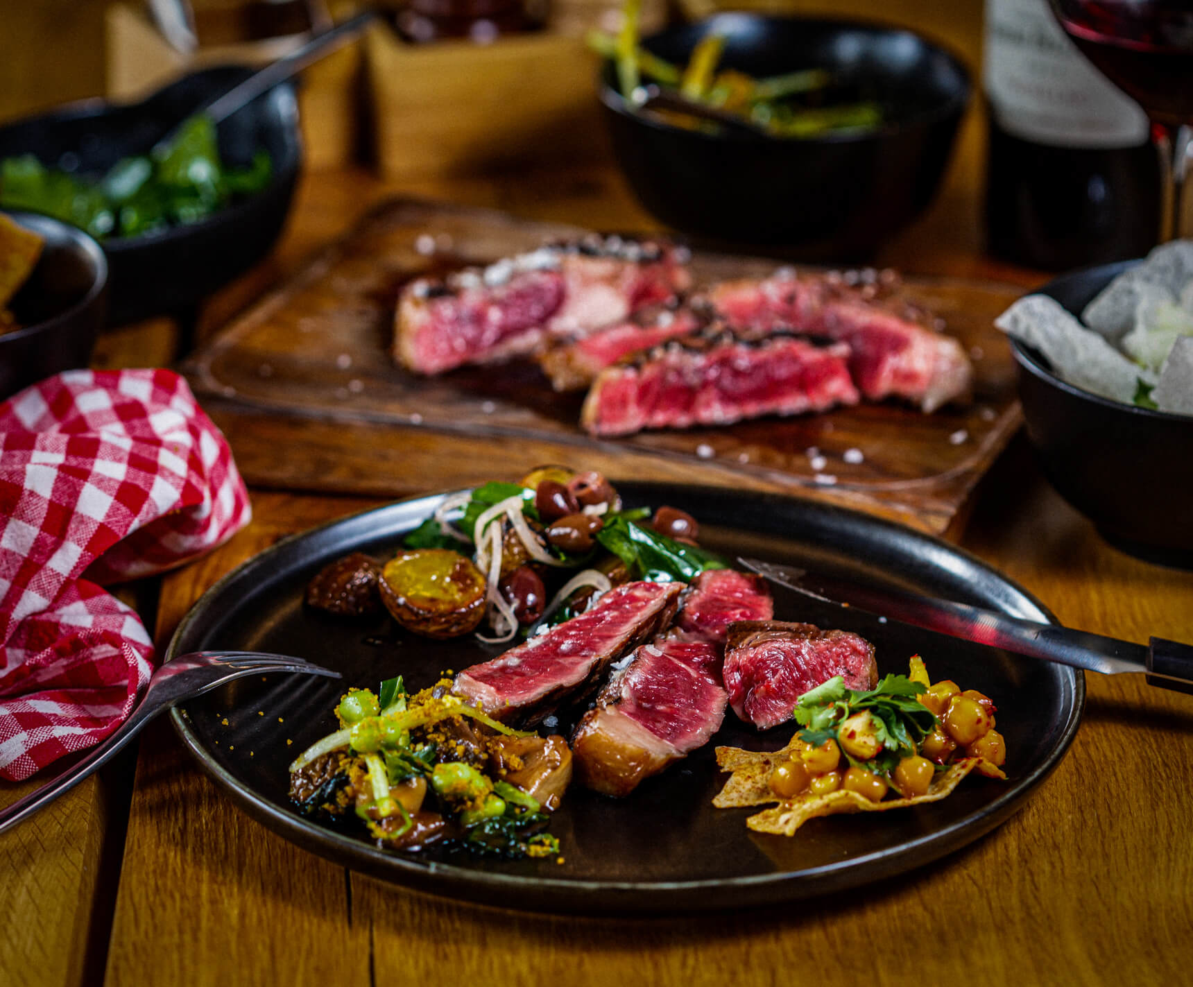 Luxusně servírovaný filetovaný steak propečený na medium rare s přílohami a sklenkou červeného vína ve stylu fine dining