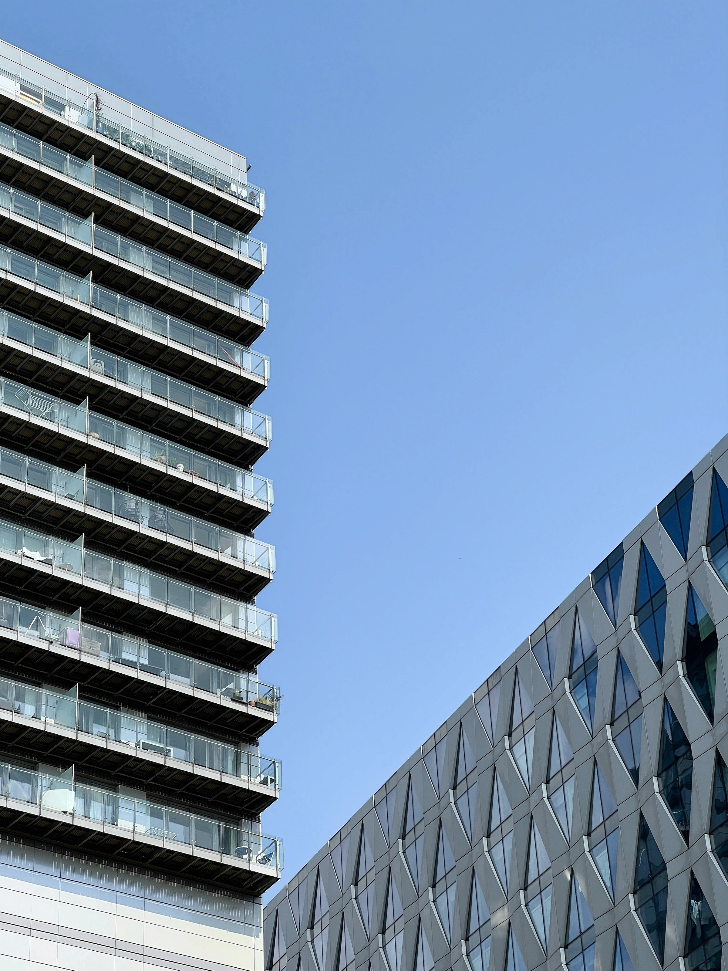 Residential tower with glass balconies and reflective facade.