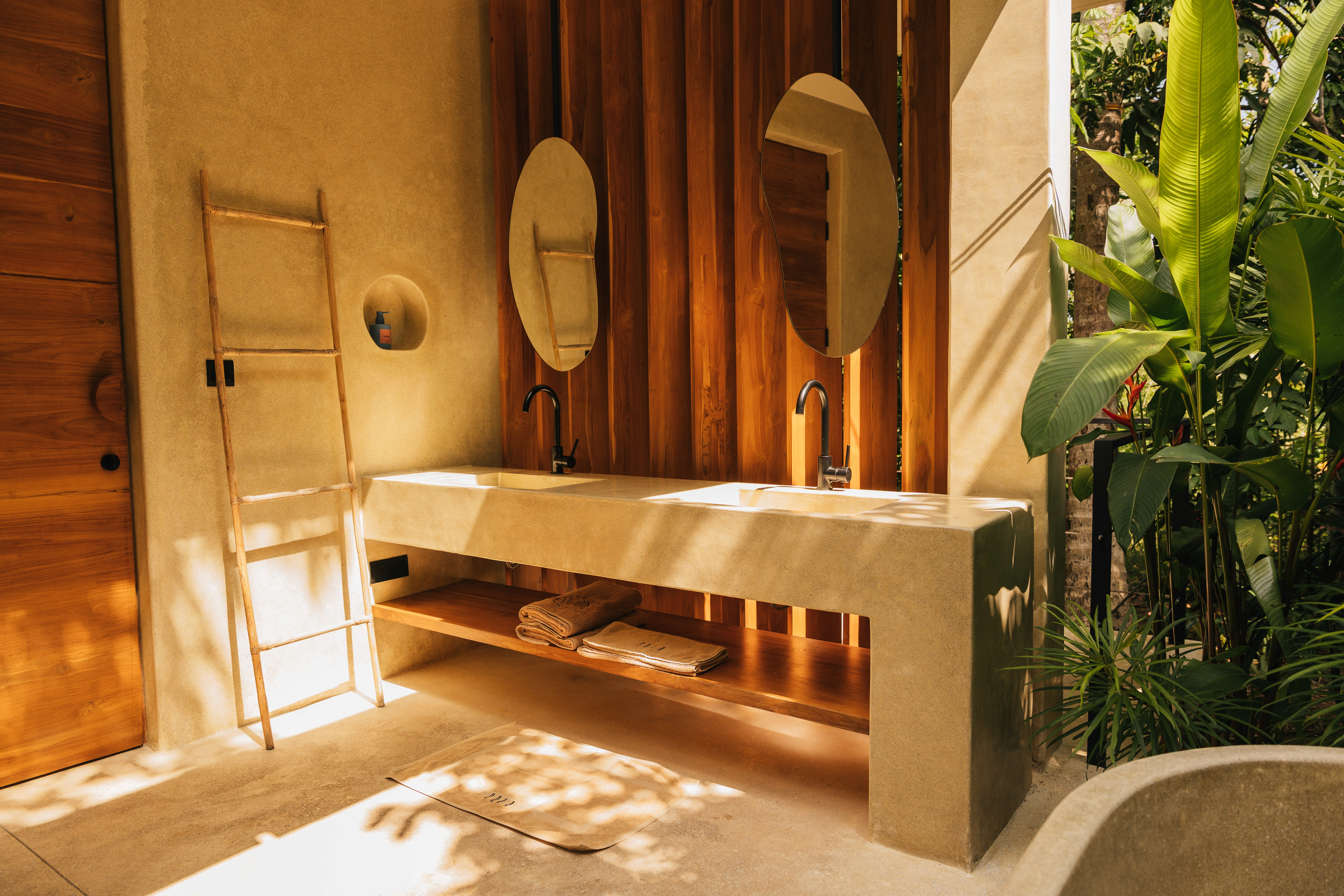 Outdoor dinning area with with chairs next to a pool surrounded by jungle