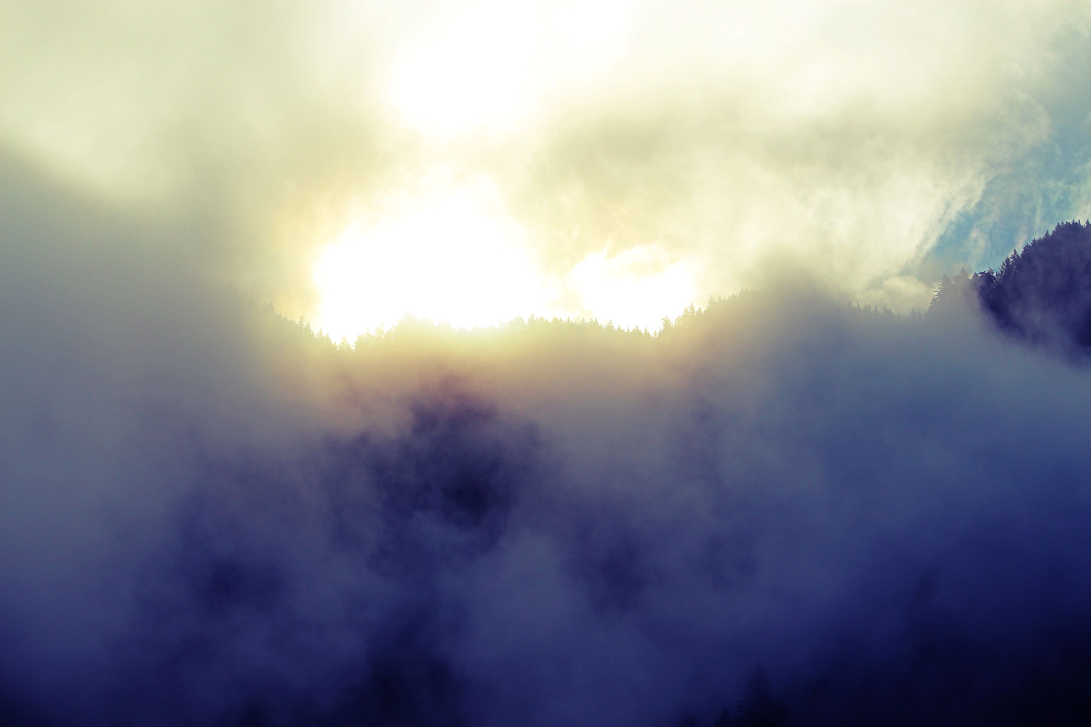 mountain shrouded in clouds with sun shining through