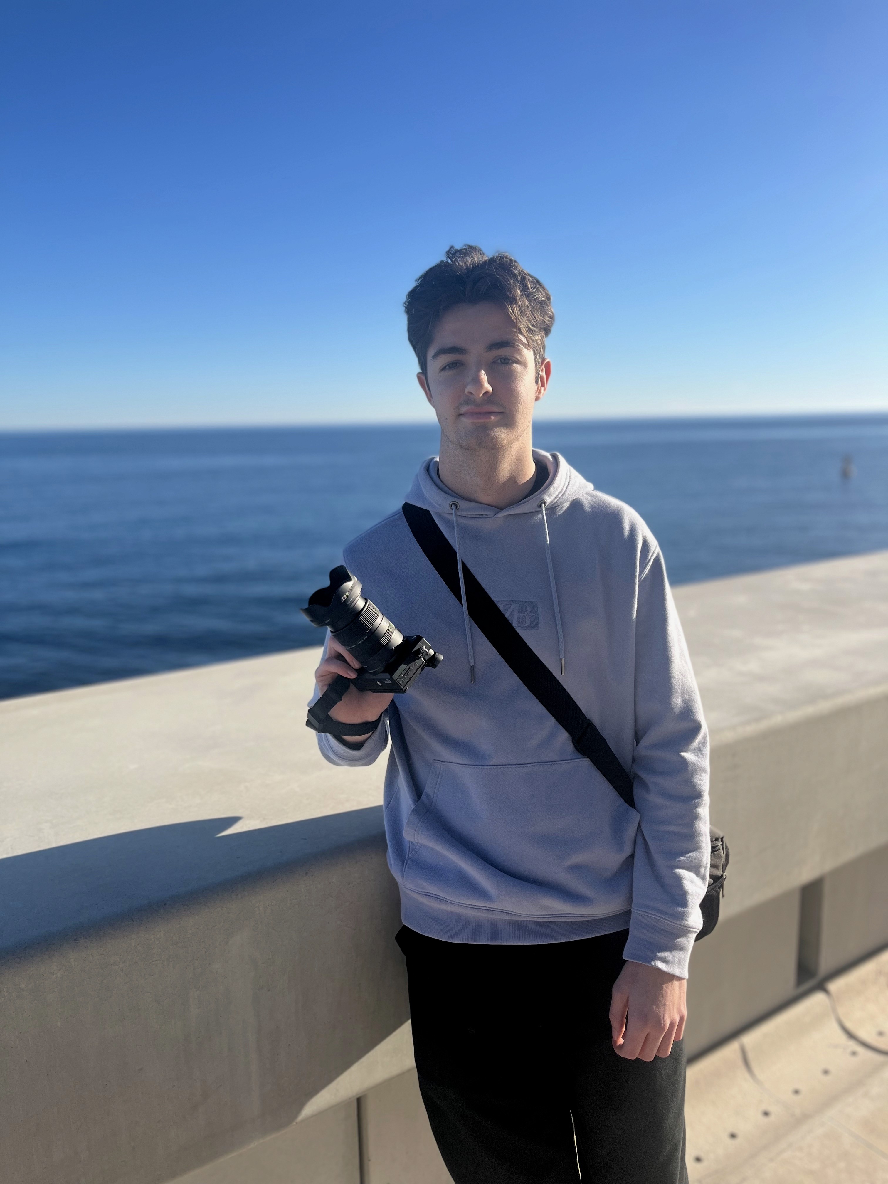A man wearing a black cap taking a photo with a Canon camera in an urban area with bokeh effects.