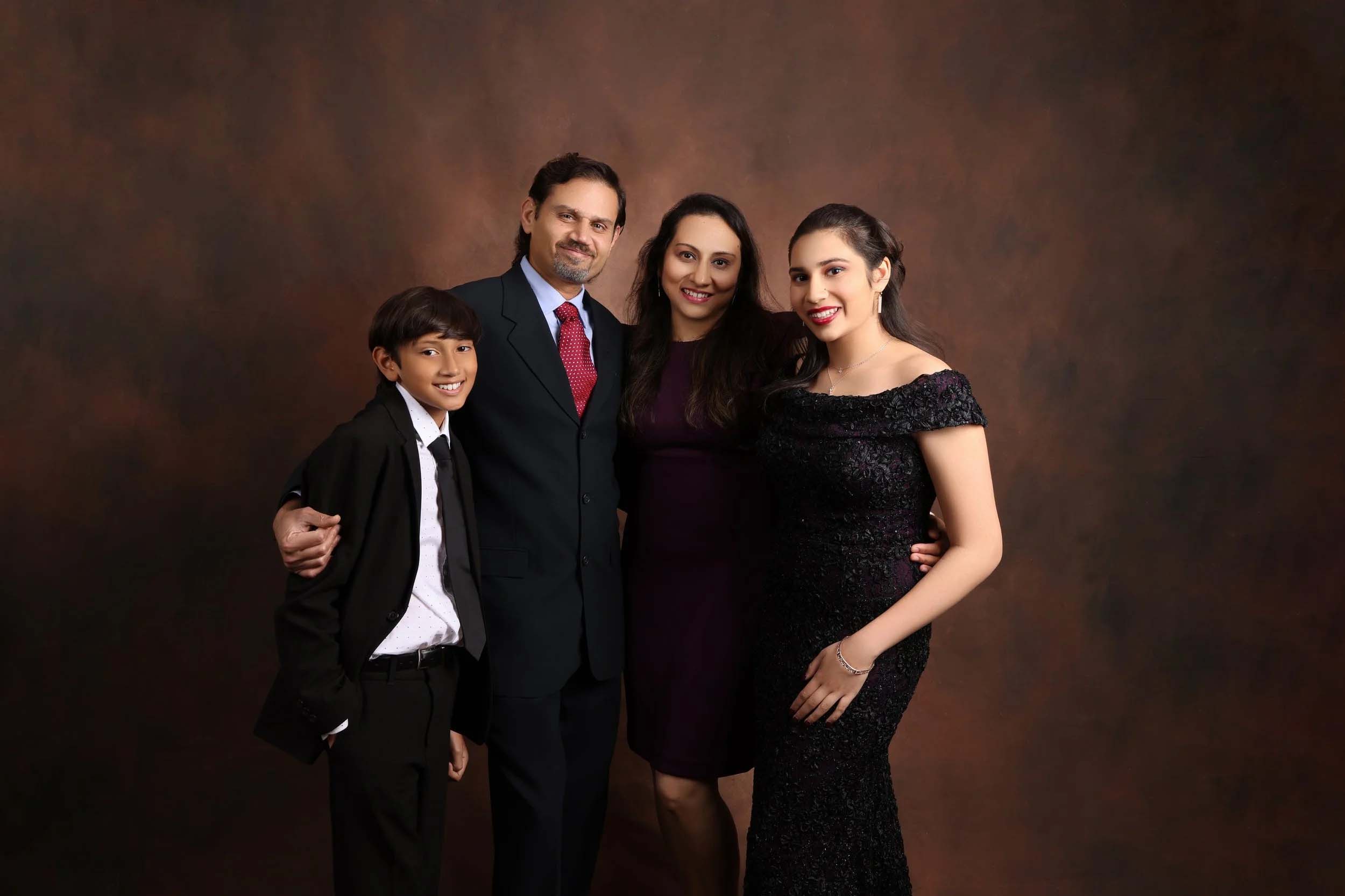 Studio family portrait of four on a warm brown backdrop