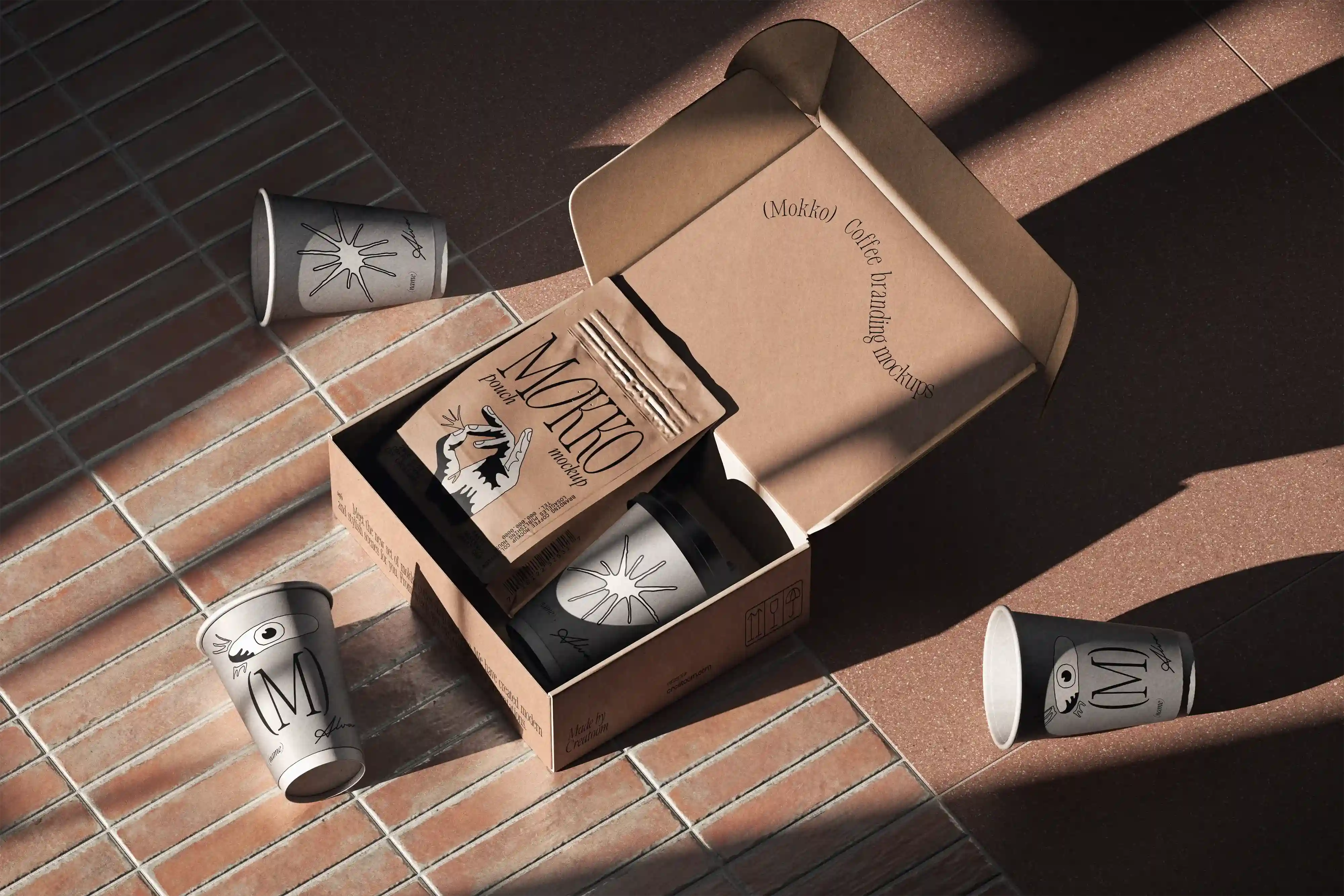 Branded coffee cups and pouches inside open cardboard box on terracotta tiles