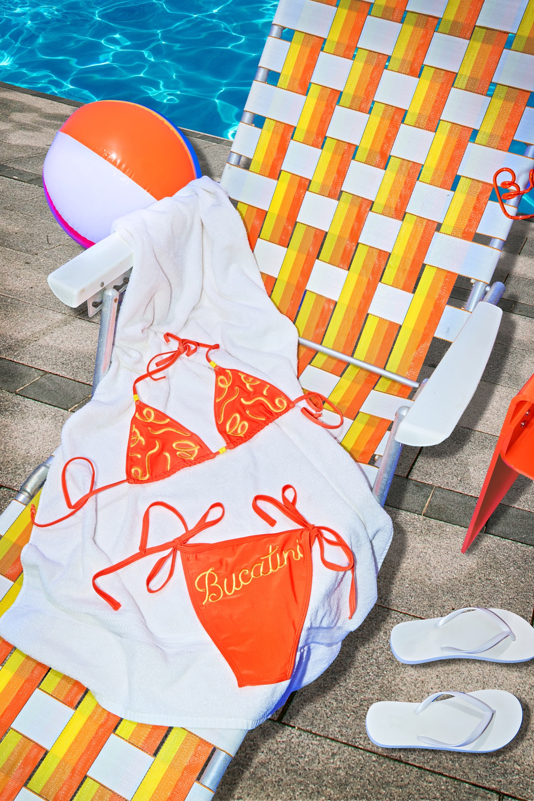 Banza Bucakini swimsuit arranged beside a striped pool chair