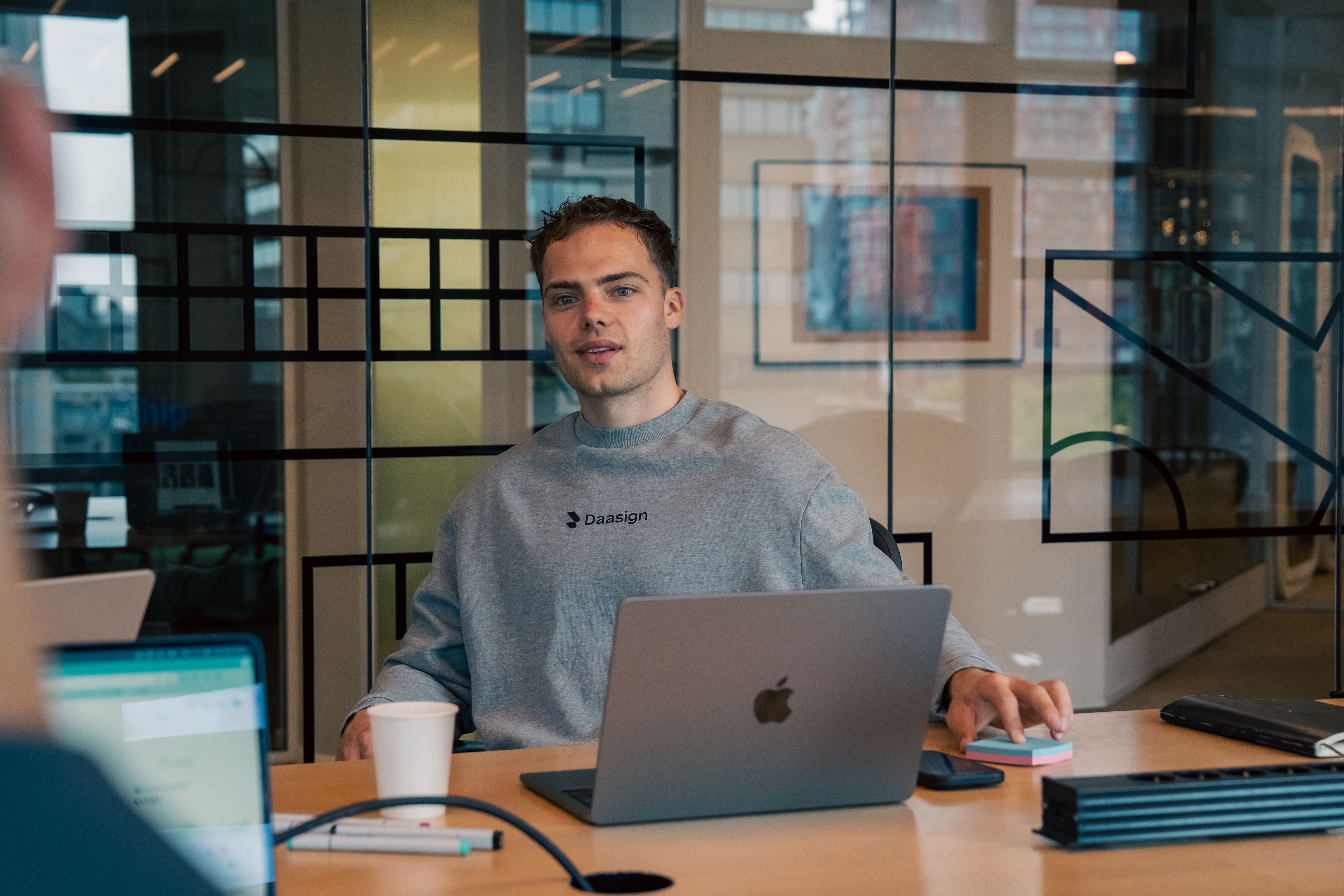 Daasign merchandise at the office with hoodie and the founder sitting with Coffee