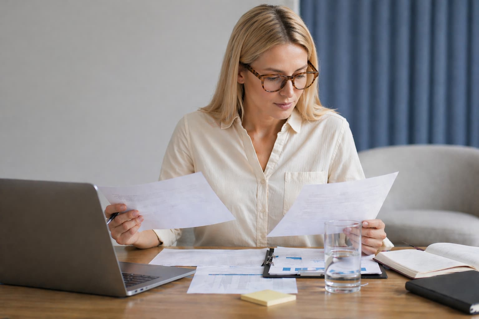 Kobieta analizująca dokumenty i dane przy laptopie