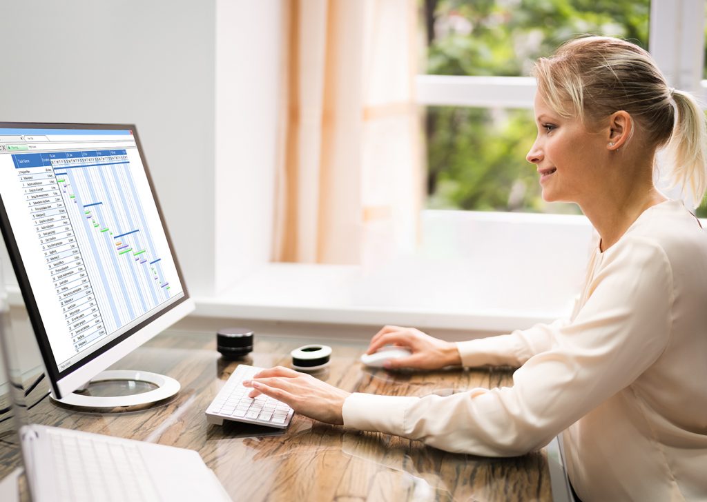 Una donna alla scrivania sta lavorando. Sul monitor il time tracking software mostra un grafico sulla produttività