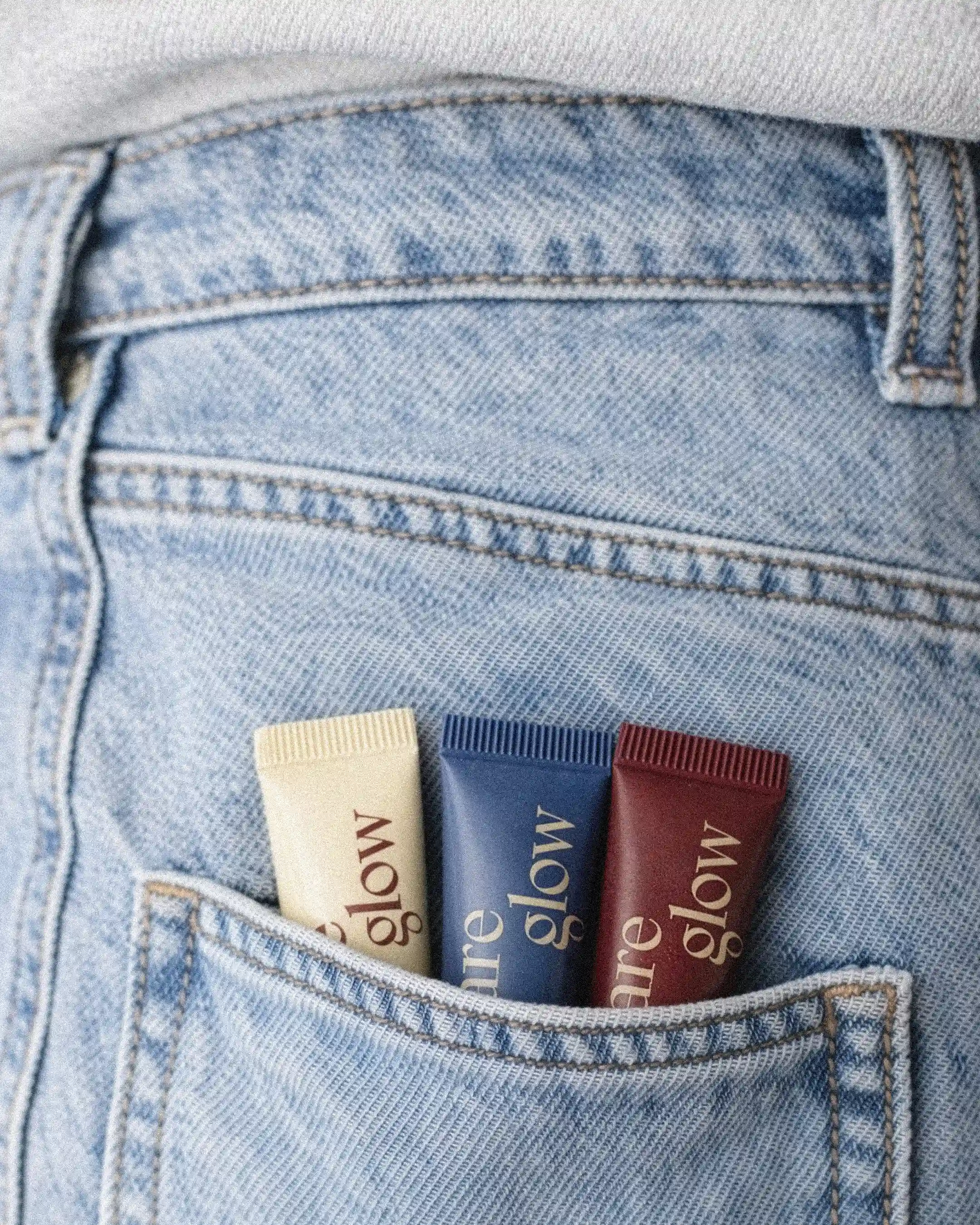 Bare Glow lip peptides tucked in denim jeans back pocket