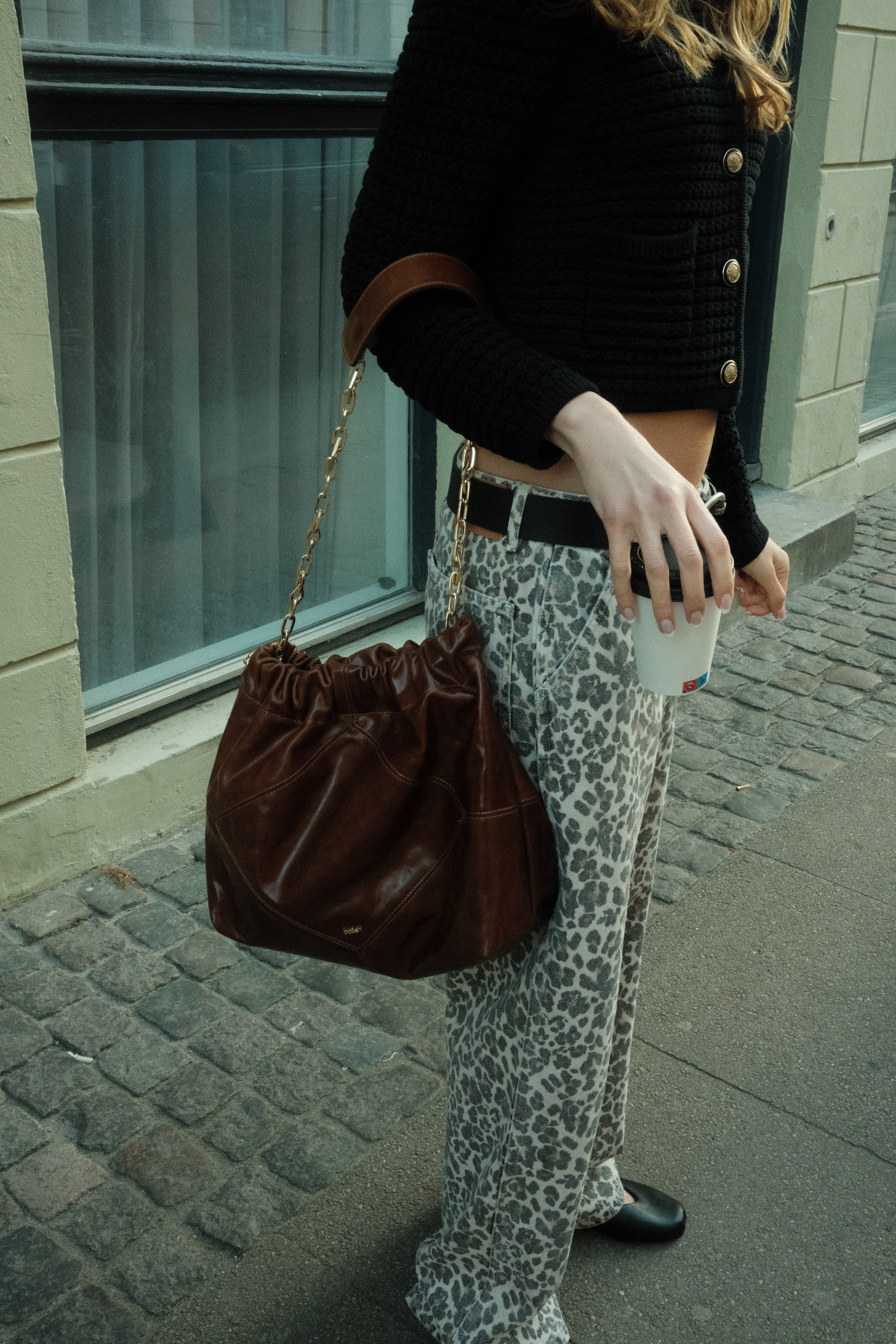 Backside of a person with a had and curly hairs sits in front of a screen in a room