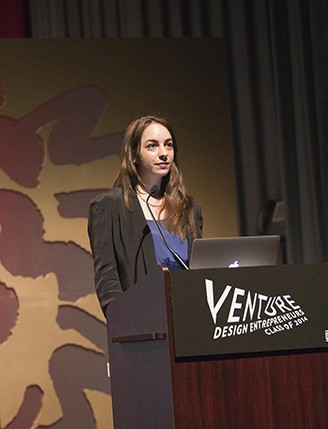 a woman giving a speech with a computer in front of her on a stand