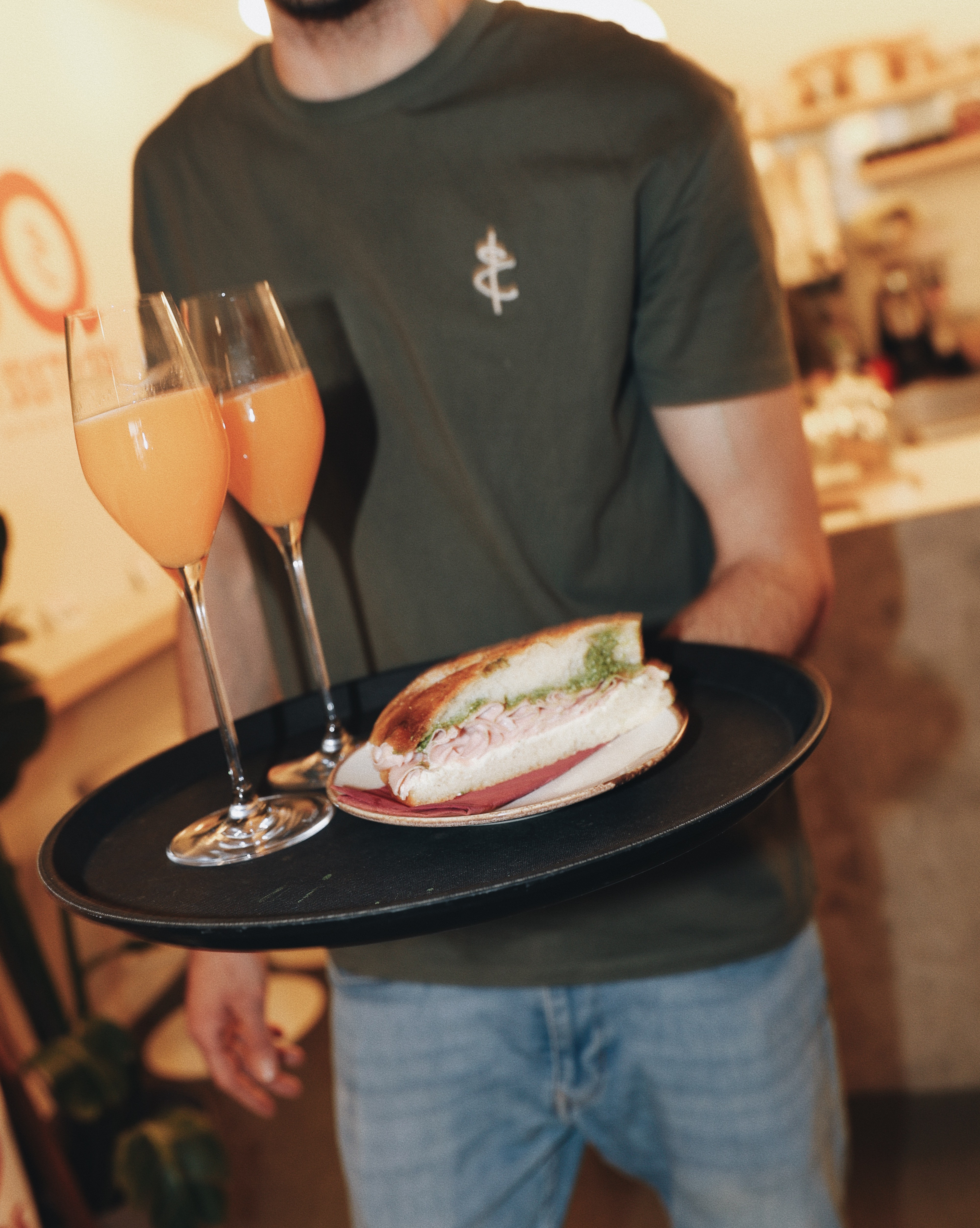 Brunch tray with sandwich and two mimosa glasses served at Jo & The Sisters Morning Club.
