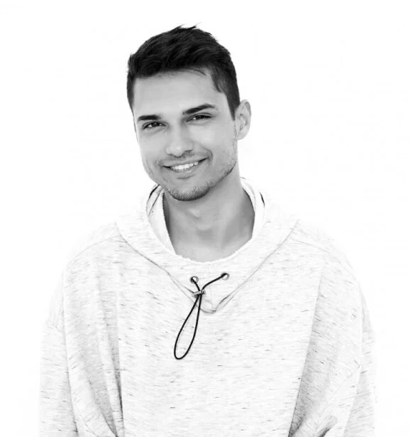 Portrait of a smiling young man with short hair, wearing a light hoodie against a plain white background