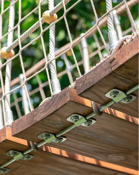Colorful bird-shaped playground slide with stairs, in a sunny park. Surrounded by trees and shops, it exudes a playful and inviting atmosphere.