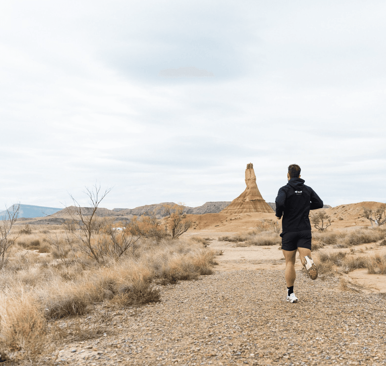 Stylish woman in a gray athletic outfit and headband standing confidently in a stadium, surrounded by empty blue seats and overhead steel beams.