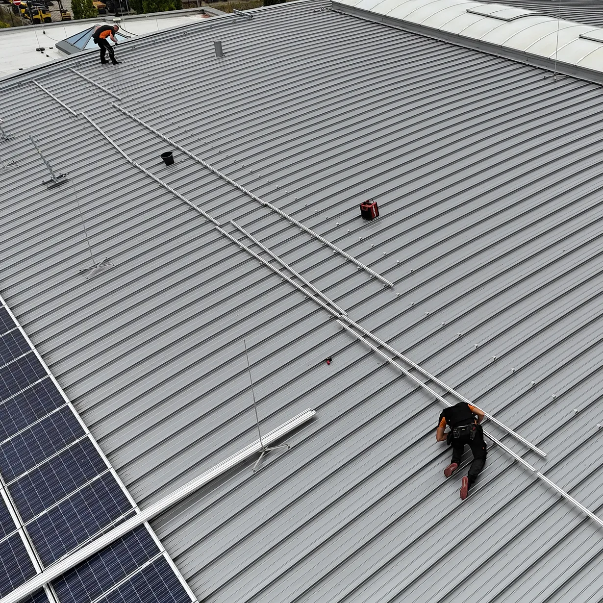 Zwei Mitarbeiter bei der Installation einer Unterkonstruktion für eine gewerbliche PV-Anlage