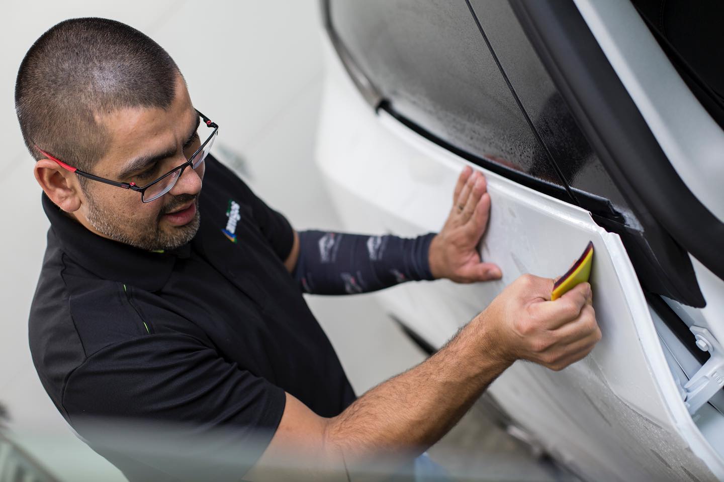 Detailer applies car film with a squeegee.
