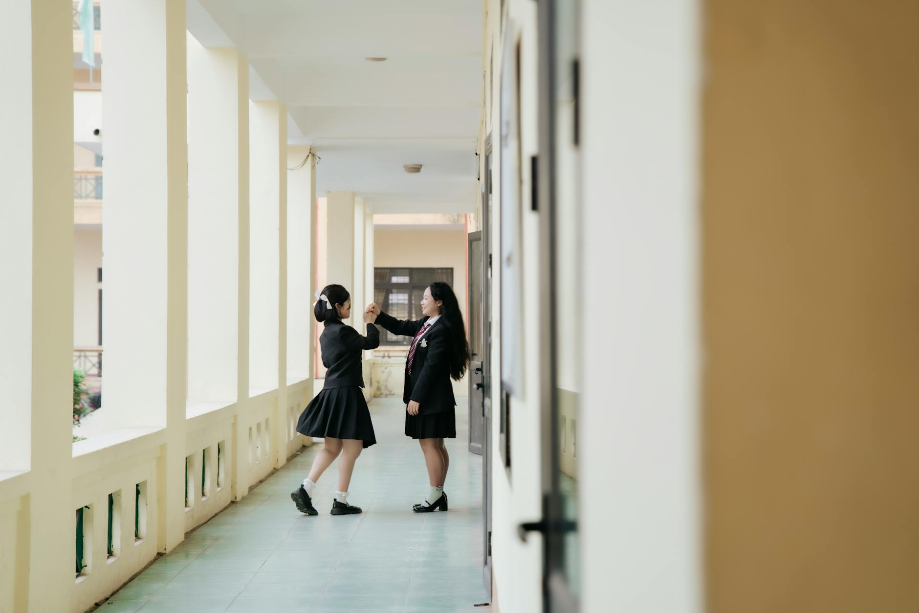 Two teenage girls laughing while working together on a colorful science poster in a secondary education setting.