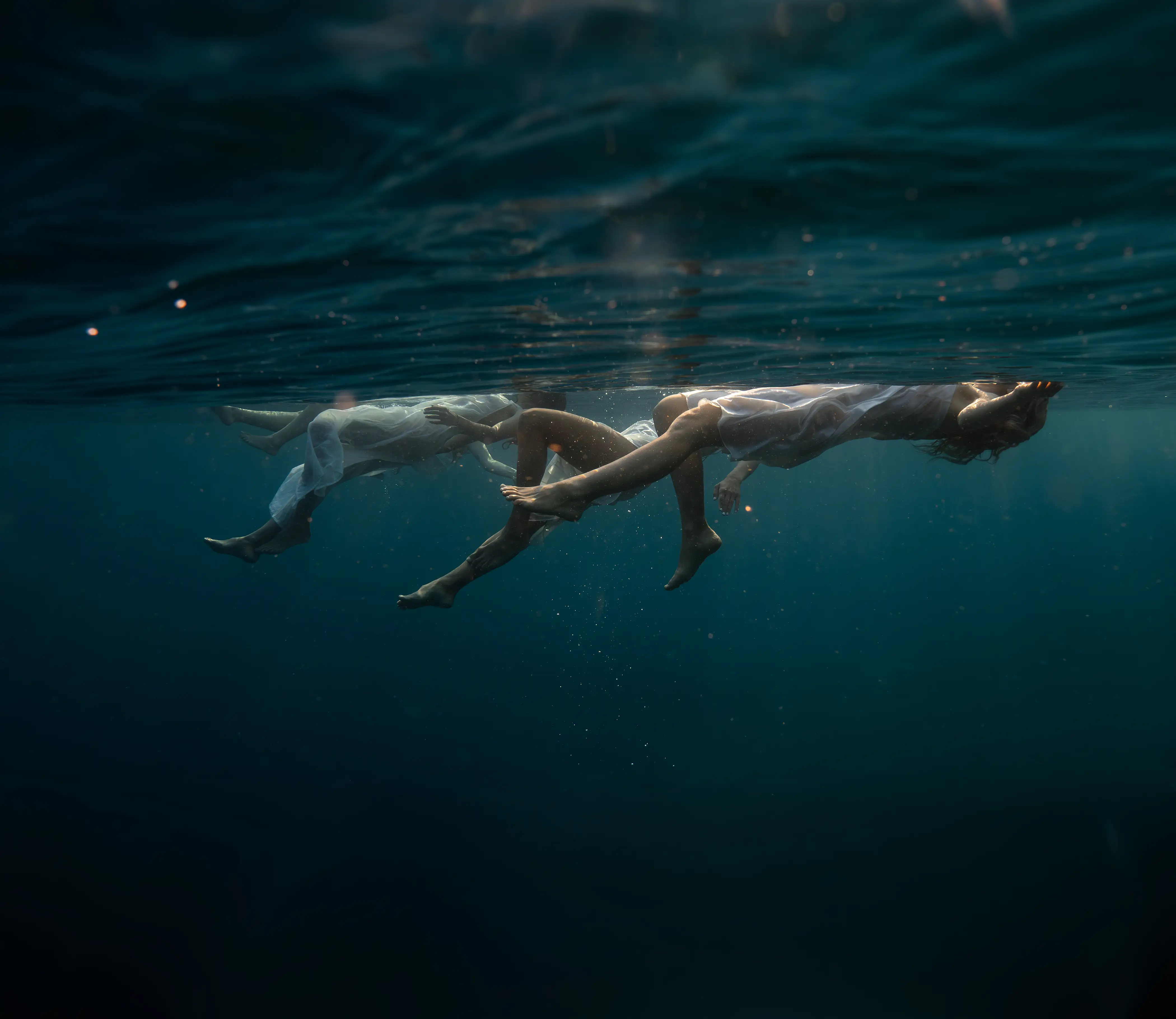 People floating serenely just below the surface of clear blue ocean water, representing the deep, data-driven approach to precision and functional medicine at BlueWave Medicine in the Bay Area.