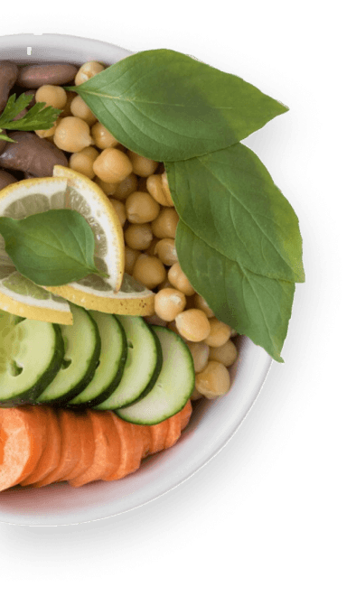 A bowl filled with sliced cucumbers, chickpeas, and carrot slices, accented by lemon wedges and garnished with basil leaves and a sprig of parsley, perfectly complements a health-focused diet.